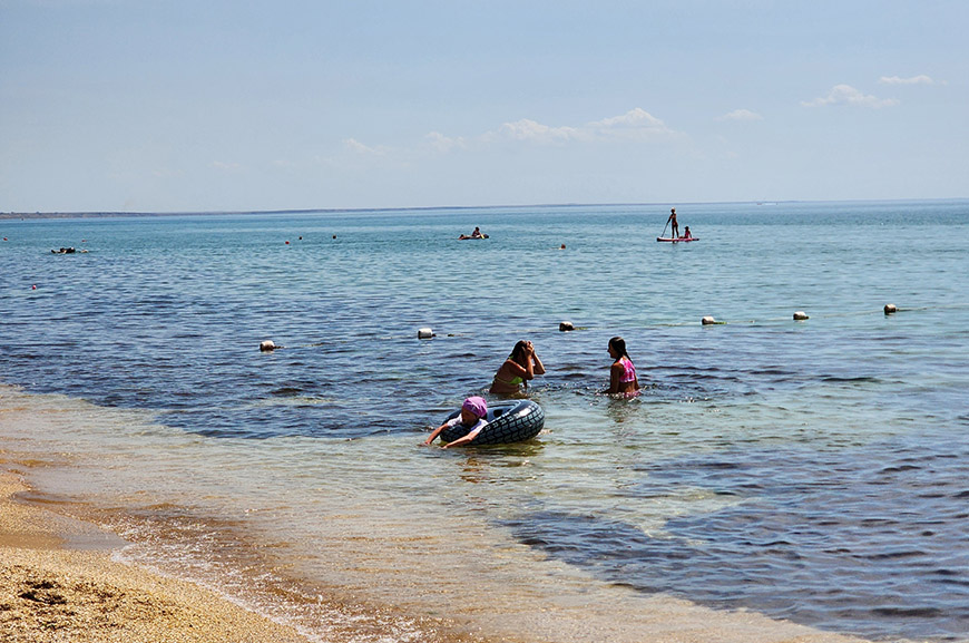 морской пляж с голубой кристально чистой водой и камнями, вид ...