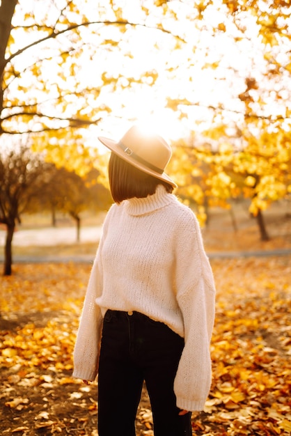 Una mujer está de pie en un parque con hojas de otoño ...